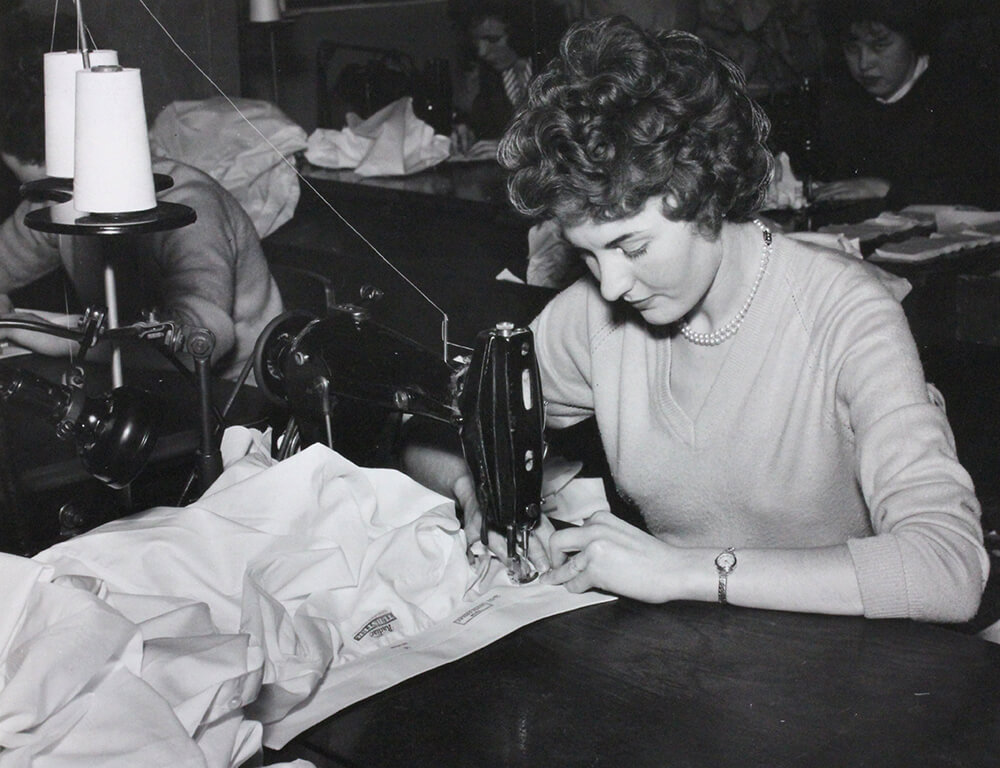 Black & white photo of City factory machinist Margaret Olphert stiching a shirt collar - 1960's